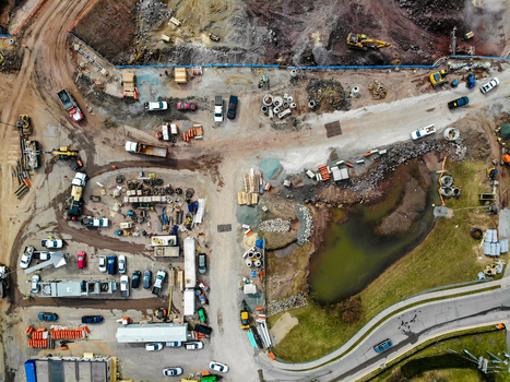 Reston Virginia United States 12 March 2019 Aerial view of a busy construction site featuring heavy machinery parked trucks building materials and a small pond. Reston Virginia United States 12 March 2019 Aerial view of a busy construction site featuring heavy machinery parked trucks building materials and a small pond.