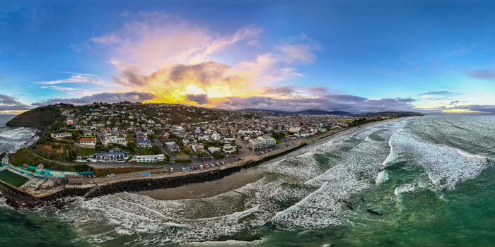 Aerial view of St Clair Beach in Dunedin with residential houses coastal cliffs and waves crashing on the shore at sunset in Dunedin Otago Region New Zealand. Aerial view of St Clair Beach in Dunedin with residential houses coastal cliffs and waves crashing on the shore at sunset in Dunedin Otago Region New Zealand.