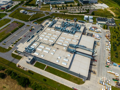 Aerial view of a large industrial manufacturing facility with flat rooftops ventilation systems and surrounding parking lots in Zebrak Central Bohemian Region Czechia. Aerial view of a large industrial manufacturing facility with flat rooftops ventilation systems and surrounding parking lots in Zebrak Central Bohemian Region Czechia.