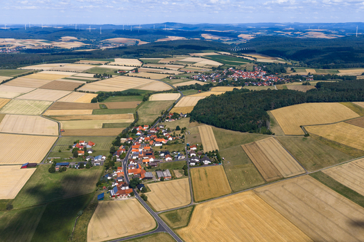 Aerial view of the rural landscape surrounding the village of Burghaun featuring patchwork agricultural fields dense forests and scattered houses in Burghaun Hessen Germany. Aerial view of the rural landscape surrounding the village of Burghaun featuring patchwork agricultural fields dense forests and scattered houses in Burghaun Hessen Germany.