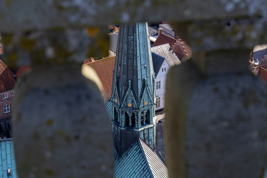View of Ribe Cathedral spire framed through stone balusters with historic red tiled rooftops in the background Ribe Denmark. View of Ribe Cathedral spire framed through stone balusters with historic red tiled rooftops in the background Ribe Denmark.