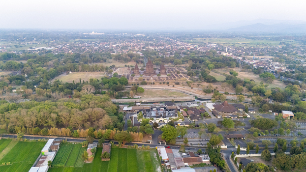 Aerial view of Prambanan Temple surrounded by lush green rice fields ancient stone structures and local vegetation in Kecamatan Prambanan Daerah Istimewa Yogya Indonesia.