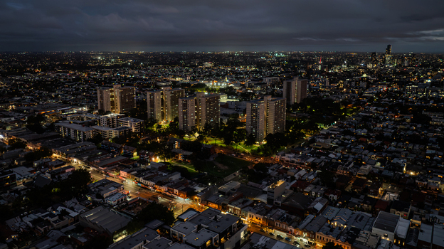 Aerial view of the illuminated urban landscape of Richmond featuring high rise residential buildings and glowing street lights at night in Richmond Victoria Australia.