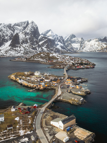 Aerial view of bridges connecting islands with vibrant turquoise waters and snow dusted mountains in the background Sakrisøya Nordland Norway. Aerial view of bridges connecting islands with vibrant turquoise waters and snow dusted mountains in the background Sakrisøya Nordland Norway.