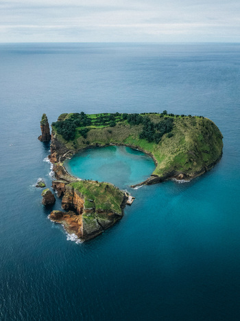 Aerial view of vibrant turquoise water encircled by verdant cliffs a hidden lagoon embraced by the vast deep blue ocean Vila Franca do Campo Azores Portugal.