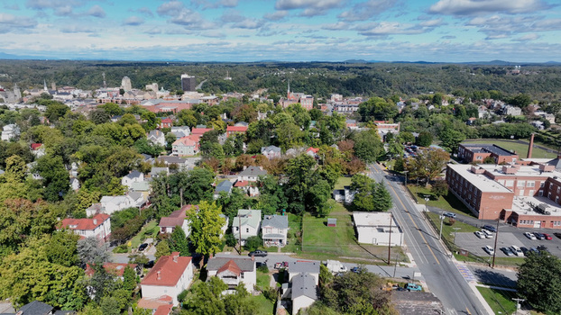 Aerial view of the cityscape of Lynchburg featuring residential neighborhoods historic architecture and dense green trees under a partly cloudy sky in Lynchburg Virginia United States. Aerial view of the cityscape of Lynchburg featuring residential neighborhoods historic architecture and dense green trees under a partly cloudy sky in Lynchburg Virginia United States.