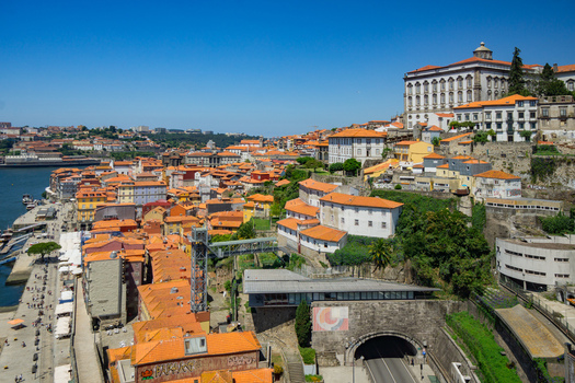Aerial view of terracotta roofs cascading down to the Douro River with the grand Porto Cathedral standing tall against the clear blue sky Porto Porto District Portugal. Aerial view of terracotta roofs cascading down to the Douro River with the grand Porto Cathedral standing tall against the clear blue sky Porto Porto District Portugal.