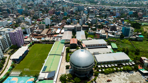 Aerial view of the American International University Bangladesh campus featuring its spherical building and sports field amidst the dense urban landscape of Dhaka Dhaka Division Bangladesh. Aerial view of the American International University Bangladesh campus featuring its spherical building and sports field amidst the dense urban landscape of Dhaka Dhaka Division Bangladesh.