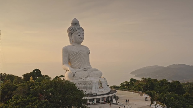 Aerial view of the Big Buddha statue perched on a hilltop surrounded by lush tropical greenery with the ocean in the background in Phuket Phuket Thailand. Aerial view of the Big Buddha statue perched on a hilltop surrounded by lush tropical greenery with the ocean in the background in Phuket Phuket Thailand.