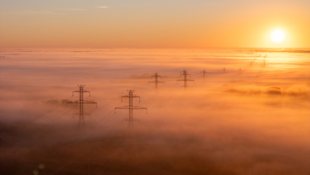 Aerial view of transmission lines and towers rising above a thick layer of morning fog at sunrise in Bridgman Michigan United States.