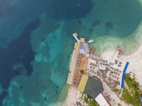 Aerial view of the Ksamil beach area with wooden piers sun loungers and umbrellas extending into the turquoise Ionian Sea in Ksamil Vlore County Albania. Aerial view of the Ksamil beach area with wooden piers sun loungers and umbrellas extending into the turquoise Ionian Sea in Ksamil Vlore County Albania.