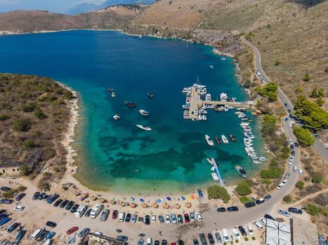 Aerial view of The Castle of Porto Palermo on a peninsula in a turquoise bay with boats at a pier a sandy beach and a coastal road in Porto Palermo Qarku i Vlores Albania.