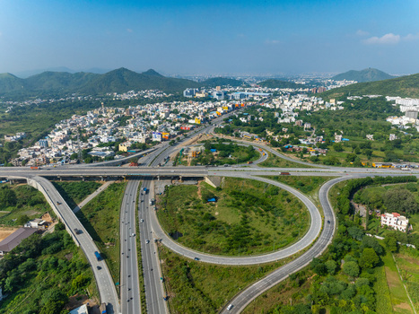 Aerial view of a modern highway interchange with looping ramps and surrounding lush green landscape near the city of Udaipur Rajasthan India. Aerial view of a modern highway interchange with looping ramps and surrounding lush green landscape near the city of Udaipur Rajasthan India.