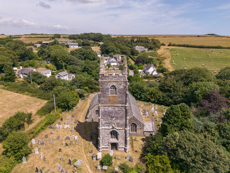 Aerial view of the historic stone church and its surrounding graveyard nestled among lush green fields and trees in the rural landscape of Lansallos England United Kingdom. Aerial view of the historic stone church and its surrounding graveyard nestled among lush green fields and trees in the rural landscape of Lansallos England United Kingdom.