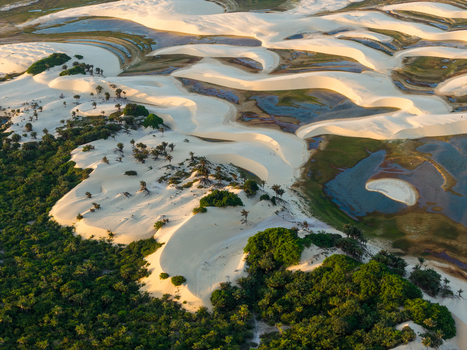 Aerial view of the white sand dunes and turquoise lagoons of Parque Nacional dos Lencois Maranhenses bordering a lush green forest Lencois Maranhenses MA Brazil. Aerial view of the white sand dunes and turquoise lagoons of Parque Nacional dos Lencois Maranhenses bordering a lush green forest Lencois Maranhenses MA Brazil.