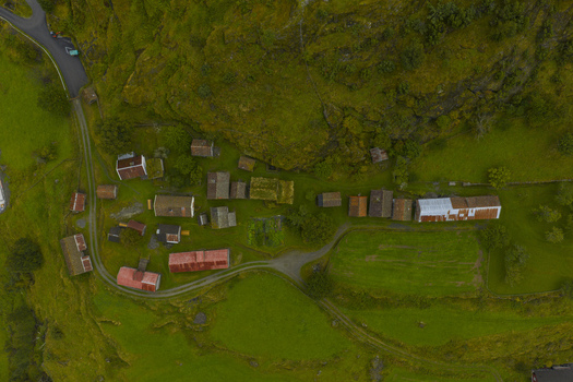 Aerial view of the historic Otternes Bygdetun farm cluster with traditional sod roofed houses nestled on a lush green hillside in Aurland Vestland Norway.
