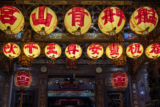 View of traditional red and yellow lanterns hanging inside a temple with ornate wooden carvings and architectural details in Guangfu Village Taipei City Taiwan. View of traditional red and yellow lanterns hanging inside a temple with ornate wooden carvings and architectural details in Guangfu Village Taipei City Taiwan.
