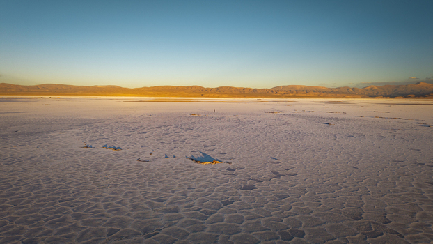 Aerial view of Salinas Grandes salt flats with a vast cracked surface under a clear blue sky at sunset in La Poma Department Salta Province Argentina. Aerial view of Salinas Grandes salt flats with a vast cracked surface under a clear blue sky at sunset in La Poma Department Salta Province Argentina.