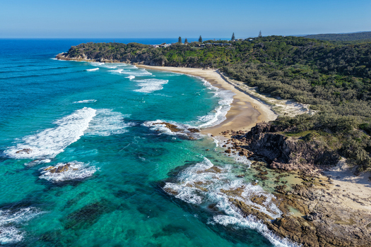 Aerial view of North Stradbroke Island coastline featuring turquoise waters sandy beach rocky outcrops and dense coastal vegetation in Redland City Queensland Australia. Aerial view of North Stradbroke Island coastline featuring turquoise waters sandy beach rocky outcrops and dense coastal vegetation in Redland City Queensland Australia.