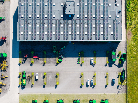 Aerial view of a farm equipment supplier facility with rooftop solar panels a parking lot with tractors and machinery and surrounding fields in Kekava Kekava Municipality Latvia. Aerial view of a farm equipment supplier facility with rooftop solar panels a parking lot with tractors and machinery and surrounding fields in Kekava Kekava Municipality Latvia.