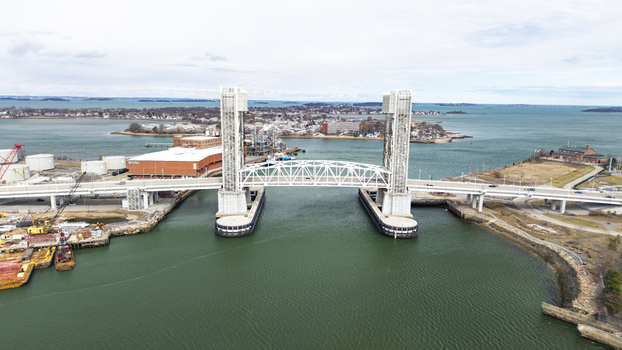 Aerial view of the bright white Fore River Bridge cutting through the emerald waters under a cloudy sky Quincy Massachusetts United States.