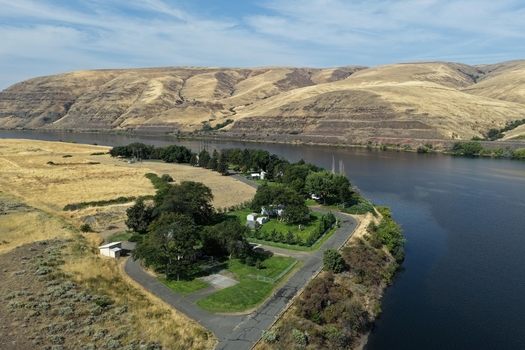 Aerial view of a residential area nestled along the riverbank surrounded by dry rolling hills and lush green trees in Whitman County Washington United States. Aerial view of a residential area nestled along the riverbank surrounded by dry rolling hills and lush green trees in Whitman County Washington United States.