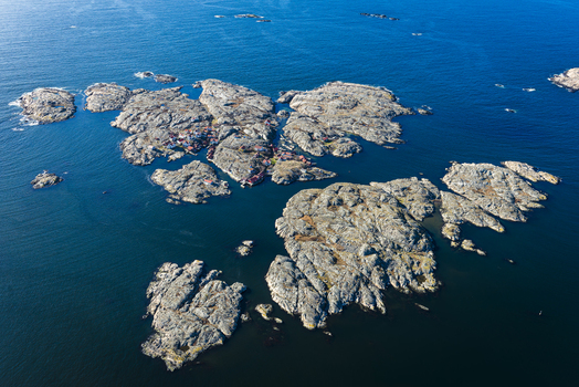 Aerial view of the rocky islands of Flatholmen in Bohuslan featuring rugged granite terrain small coastal houses and deep blue sea in Skarhamn Vastra Gotalands lan Sweden.