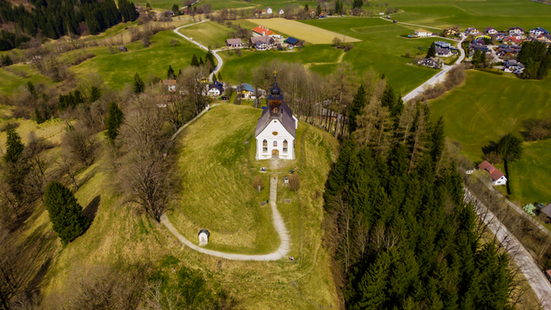 Aerial view of a solitary white church perched atop a hill offering a striking contrast against the vivid green valley Windischgarsten Upper Austria Austria. Aerial view of a solitary white church perched atop a hill offering a striking contrast against the vivid green valley Windischgarsten Upper Austria Austria.