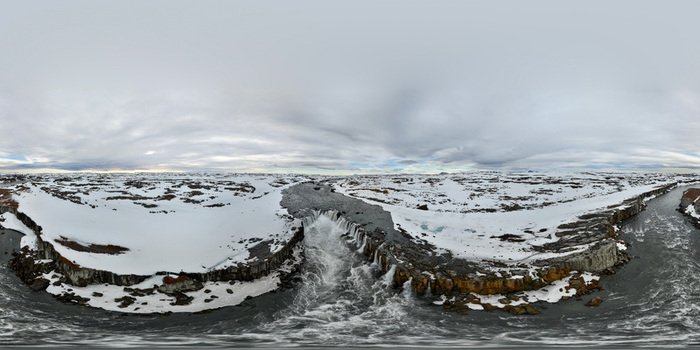 Aerial view of Selfoss waterfall cascading through a rocky canyon surrounded by snow covered plains under an overcast sky Selfoss Sveitarfelagid Arborg Iceland.