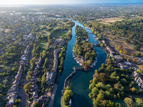 Aerial view of Hampton Court and the River Thames with Garrick s Ait island boats and surrounding residential areas in Molesey England United Kingdom. Aerial view of Hampton Court and the River Thames with Garrick s Ait island boats and surrounding residential areas in Molesey England United Kingdom.