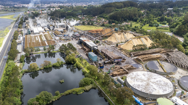 Aerial view of the Biofabrica de Ence pulp mill with large wood chip piles and water treatment tanks surrounded by green hills in Pontevedra Pontevedra Spain. Aerial view of the Biofabrica de Ence pulp mill with large wood chip piles and water treatment tanks surrounded by green hills in Pontevedra Pontevedra Spain.