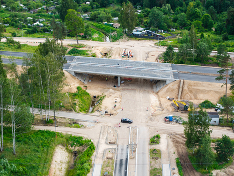 Aerial view of the Southern Bridge project construction site featuring a concrete overpass heavy machinery and surrounding greenery in Riga Latvia. Aerial view of the Southern Bridge project construction site featuring a concrete overpass heavy machinery and surrounding greenery in Riga Latvia.