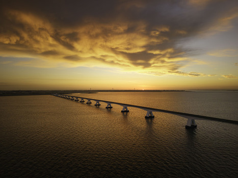 Aerial view of Zeeland Bridge stretching across the Oosterschelde estuary during a vibrant sunrise with golden light reflecting on the water in Zierikzee Zeeland Netherlands. Aerial view of Zeeland Bridge stretching across the Oosterschelde estuary during a vibrant sunrise with golden light reflecting on the water in Zierikzee Zeeland Netherlands.