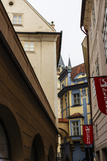 Prague Czechia 25 November 2022 View of historic buildings with colorful facades and red museum banners along a narrow street in the old town.