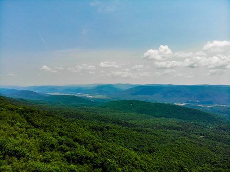 Lost City West Virginia United States 12 June 2019 Aerial view of the lush green Appalachian Mountains featuring dense forest canopy under a bright blue sky with scattered clouds. Lost City West Virginia United States 12 June 2019 Aerial view of the lush green Appalachian Mountains featuring dense forest canopy under a bright blue sky with scattered clouds.