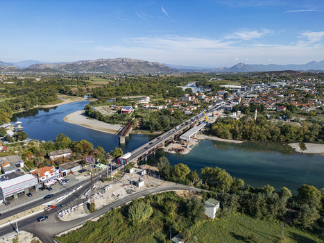 Aerial view of Ura e Bahcallekut bridge spanning the Drin River with ongoing construction surrounding greenery and the town of Bahcallek in Bahcallek Shkoder County Albania. Aerial view of Ura e Bahcallekut bridge spanning the Drin River with ongoing construction surrounding greenery and the town of Bahcallek in Bahcallek Shkoder County Albania.