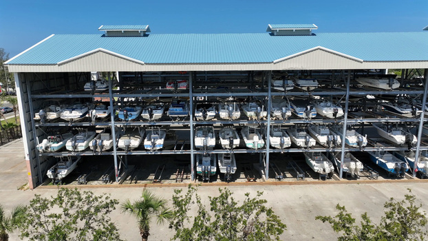 Aerial view of a multi level dry stack boat storage facility filled with various motorboats under a blue metal roof in Cortez Florida United States.
