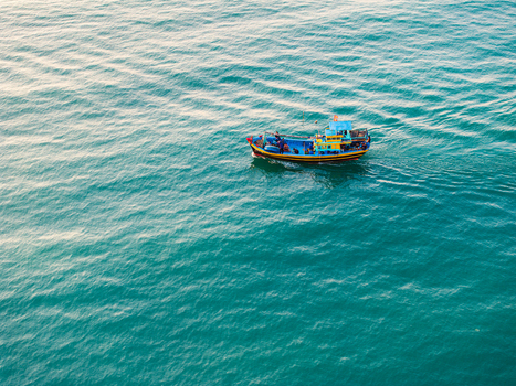 Aerial view of a small colorful fishing boat sailing on the turquoise sea in Vietnam. Aerial view of a small colorful fishing boat sailing on the turquoise sea in Vietnam.