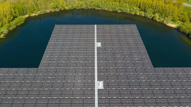 Aerial view of a large floating solar panel array on a calm lake surrounded by lush green trees in Zwolle Overijssel Netherlands. Aerial view of a large floating solar panel array on a calm lake surrounded by lush green trees in Zwolle Overijssel Netherlands.