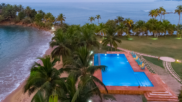 Axim Western Region Ghana 09 February 2023 Aerial view of Lou Moon Resort Eco Luxury featuring a swimming pool surrounded by palm trees and the coastline. Axim Western Region Ghana 09 February 2023 Aerial view of Lou Moon Resort Eco Luxury featuring a swimming pool surrounded by palm trees and the coastline.
