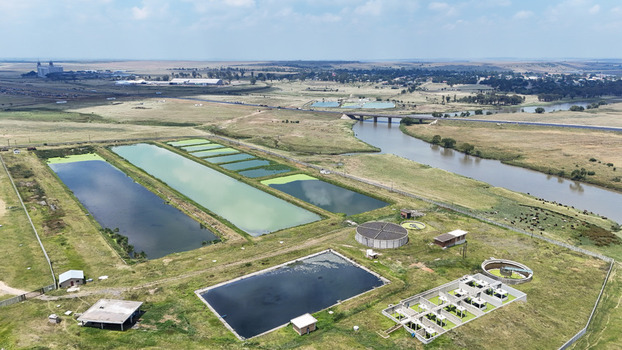 Aerial view of the Vaal River flowing past a water treatment facility with settling ponds and green fields in Villiers Free State South Africa. Aerial view of the Vaal River flowing past a water treatment facility with settling ponds and green fields in Villiers Free State South Africa.