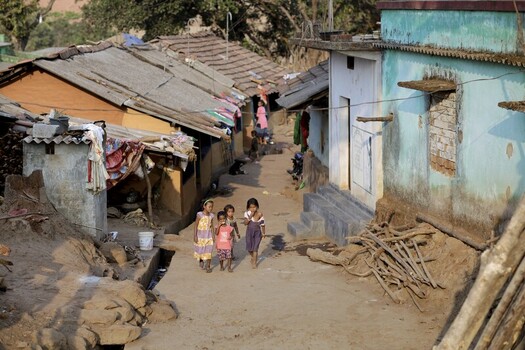 Odisha India 26 March 2026 View of children walking along a worn path between rustic homes with weathered roofs and colorful walls creating a scene of daily life. Odisha India 26 March 2026 View of children walking along a worn path between rustic homes with weathered roofs and colorful walls creating a scene of daily life.