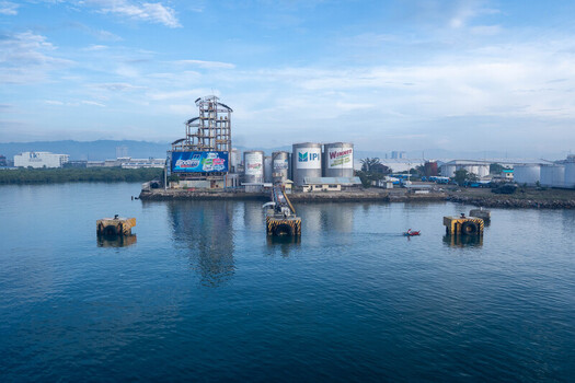 Cebu Central Visayas Philippines 23 September 2026 View of the industrial port facility in Cebu with storage tanks silos and a small boat on the water. Cebu Central Visayas Philippines 23 September 2026 View of the industrial port facility in Cebu with storage tanks silos and a small boat on the water.