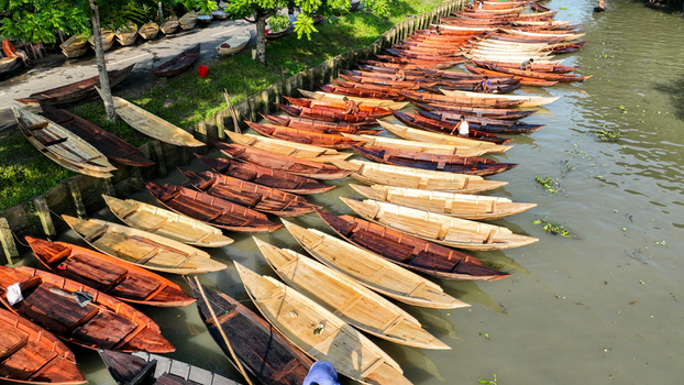 Aerial view of traditional wooden boats lined up along the waterway their warm brown hues contrasting with the green foliage Pirojpur Pourashava Bangladesh. Aerial view of traditional wooden boats lined up along the waterway their warm brown hues contrasting with the green foliage Pirojpur Pourashava Bangladesh.