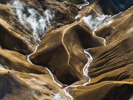 Aerial view of winding glacial rivers carving through the volcanic landscape with steam rising from geothermal vents Landmannalaugar Iceland.