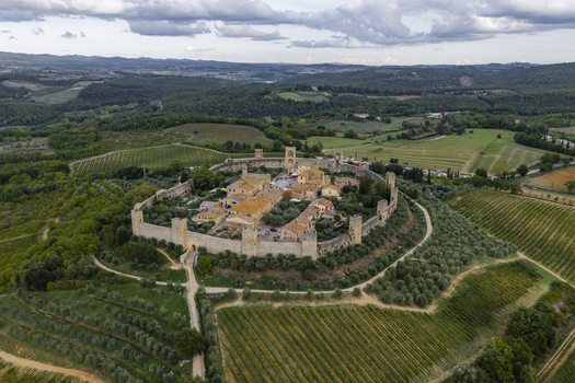 Aerial view of the historic medieval walled town of Monteriggioni with its stone fortifications terracotta rooftops and surrounding vineyards and olive groves in Monteriggioni Tuscany Italy.