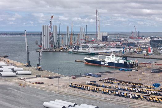 Esbjerg Denmark 24 July 2026 Aerial view of Esbjerg Port with wind turbine components a DFDS cargo ship docked at the quay and numerous trucks parked in the logistics area under a cloudy sky.
