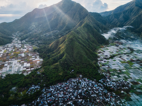 Aerial view of the Sembalun agricultural basin at the foothills of Mount Rinjani featuring patchwork rice fields lush mountain slopes and a village in Sembalun West Nusa Tenggara Indonesia. Aerial view of the Sembalun agricultural basin at the foothills of Mount Rinjani featuring patchwork rice fields lush mountain slopes and a village in Sembalun West Nusa Tenggara Indonesia.
