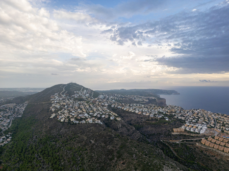 Aerial view of the coastal town of Moraira on a hillside overlooking the Mediterranean Sea featuring residential villas and winding roads in Moraira Valencian Community Spain.