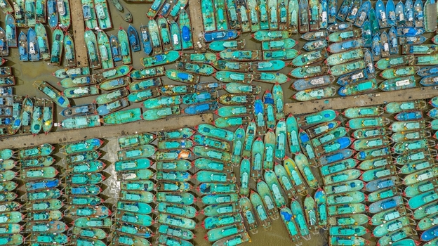 Aerial view of Malpe Fishing Harbour with numerous colorful fishing boats docked in rows in the calm waters of Udupi Karnataka India. Aerial view of Malpe Fishing Harbour with numerous colorful fishing boats docked in rows in the calm waters of Udupi Karnataka India.